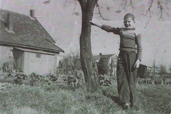 Jaren 50 Jan de valk in de tuin van het ouderlijk huis op de achtergrond de Vivo Winkel van de fam H.Arts bron Hanny de Valk